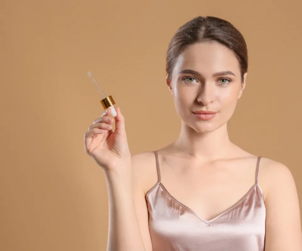 Woman applying Aurelle Vitamin C serum with a glass dropper